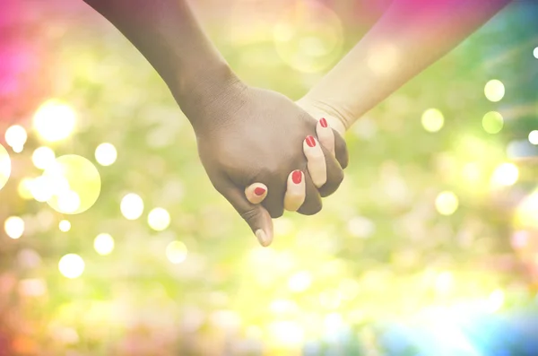 Primer plano en una pareja de razas mixtas cogidas de la mano en el parque —  Fotos de Stock