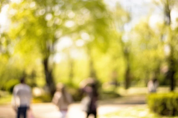 Parkta yürüyüş insanların doğal bokeh arka plan. — Stok fotoğraf