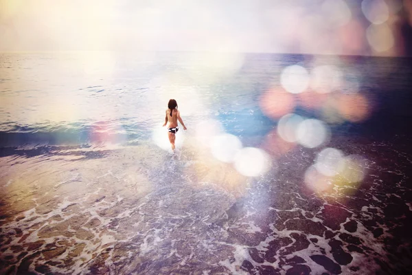 Chica feliz corriendo en la playa, imagen desenfocada borrosa con bo — Foto de Stock