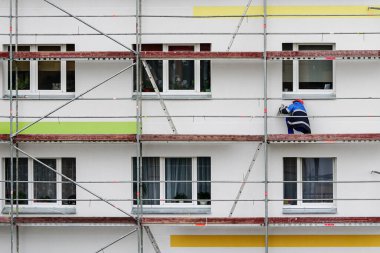 İşçi, bir apartman dairesinin ön cephesinin tadilatını tamamlar.