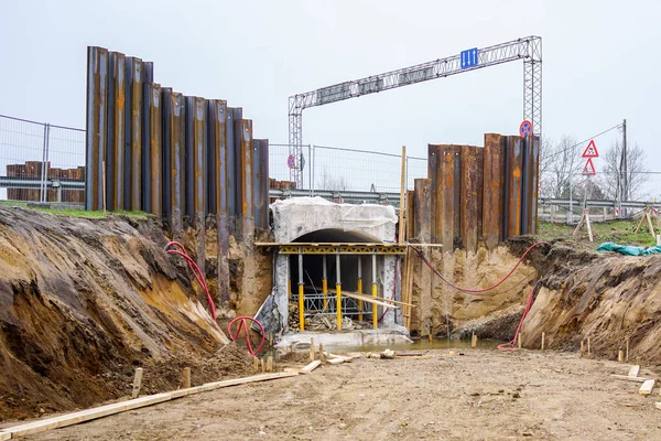 construction of a pedestrian tunnel under the highway, temporary metal retaining wall support the foundation