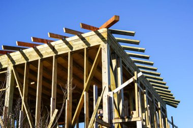 Yeni modern ahşap ev iskeleti yapım aşamasında, mavi gökyüzü arkaplanı