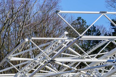 Mavi gökyüzünün arka planında yeni bir modern binanın beyaz metal iskeletinin bir parçası.