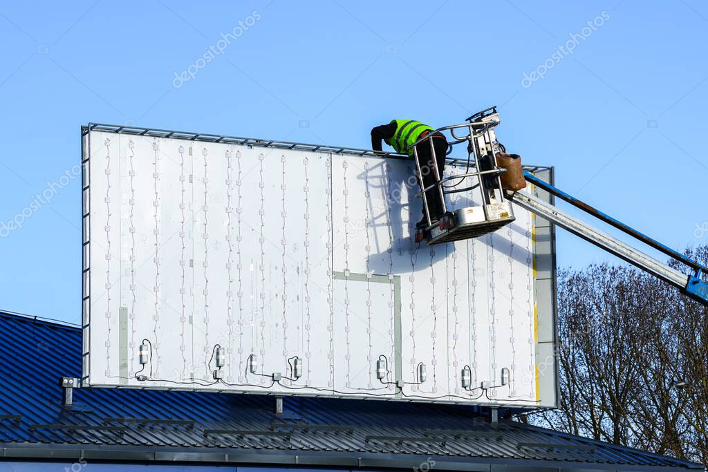 installation of a new large modern billboard with LED lighting on a background of blue sky