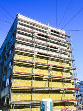Bir apartman dairesinin dış cephesinin termal yalıtımının kurulumu, mavi gökyüzü arka planı