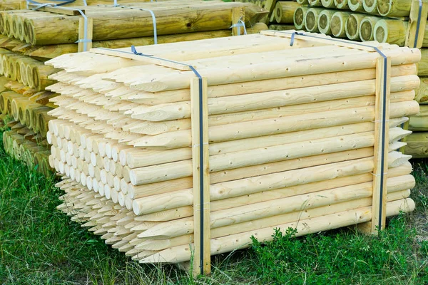 pallet with long round natural wooden fence posts with a sharpened tip