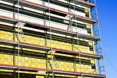 Bir apartman dairesinin dış cephesinin termal yalıtımının kurulumu, mavi gökyüzü arka planı