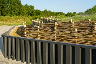 Kumsal altyapısını kum tepelerinin hareketlerinden korumak için yeni bir hasır söğüt dalı bariyeri.