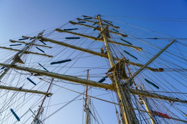 Büyük yelkenli gemi direkleri mavi gökyüzü arka planında bir sürü halatla