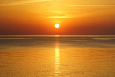 Baltık Denizi 'nde güzel bir gün batımı, ufukta güneş ve suda yansıma.