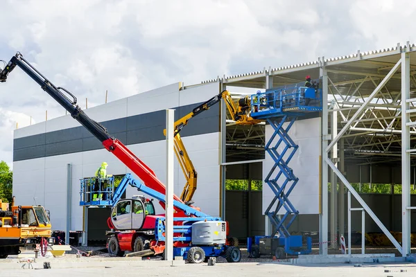 a sandwich panel wall is mounted with the help of a modern telescopic crane and scissor lifts