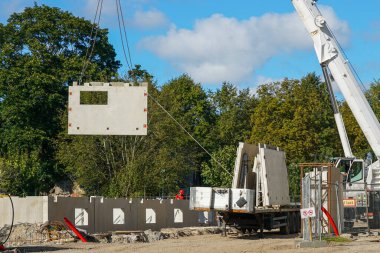 Binanın montajında modern yöntemler kullanan büyük vinç, çok katlı inşaat sahasında önceden yapılmış beton panel kaldırdı
