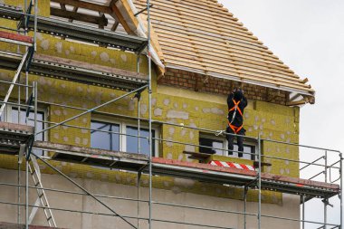 İnşaat işçisi ön cephe yalıtımında mineral yünü, dış duvar yenilenmesi, çatı ve ev inşaatında çalışıyor.