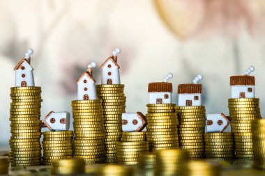 Gayrimenkul yatırımı, ipotek, emlak değeri, konut piyasası büyümesi veya iflası temsil eden altın sikkeler üzerindeki küçük ev modelleri