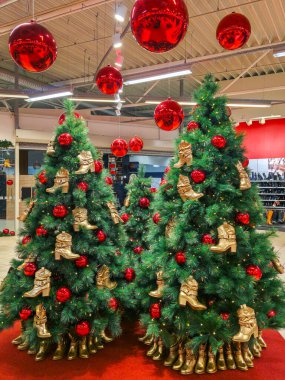 Ayakkabı mağazasındaki şık Noel ağacı, altın çizmeler, kırmızı mücevherlerle süslenmiş, eşsiz bir bayram perakendecisi, harmanlanmış moda ve şenlikli dekorasyon yaratıyor.