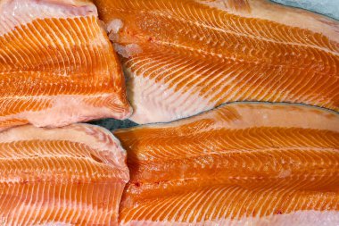 Buzun üzerine serilmiş taze somon filetolarının yakın plan görüntüsü, zengin portakal rengi, doğal doku ve pazarlar için kaliteli deniz ürünleri vurgulanıyor.