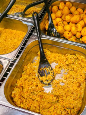 Baharatlı pirinç, köri sosu ve baharatlı patatesle dolu paslanmaz çelik tepsilerle servis büfesi matarada servis için hazır.