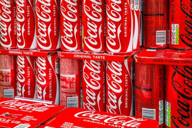 Liepaja, Letonya - 12. Aralık 2025: Raflara istiflenmiş Coca-Cola kutuları, ikonik kırmızı markalaşma ve içecek perakendecisi görüntülerini vurguluyor