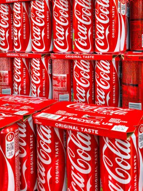 Liepaja, Letonya - 12. Aralık 2025: Orijinal Coca-Cola kutuları ve çoklu paketler bir mağaza rafında, markalaşma ve perakende sergileniyor.
