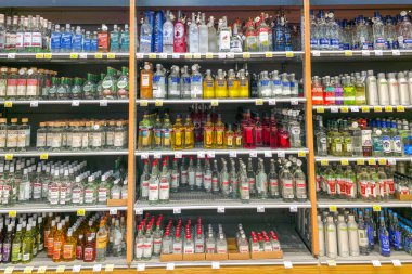 Liepaja, Letonya - 04. Ocak 2026: Süpermarkette alkol reyonunda raflarda fiyat etiketleri ve güvenlik şişe kapaklarıyla çeşitli votka markaları sergileniyor