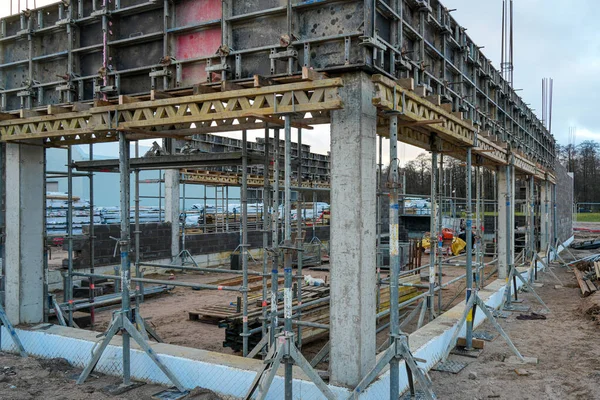 İnşaat alanı, inşaat işleri, sütunlar, destekler, iskeleler ve ticari bir bina için yapısal temeller hazırlayan işçileri gösteriyor.