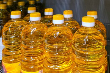 Sıraya dizilmiş sarı yağ ile dolu çoklu plastik şişelerin yakın çekimi, perakende gıda arzını ve yenilebilir yağ ambalajını gösteriyor
