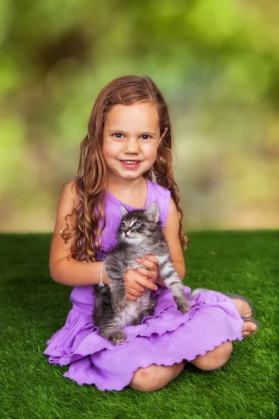 Meisje met katje buiten op gras — Stockfoto