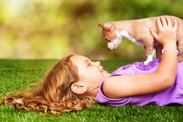 Glückliche Mädchen und Welpen liegen auf Gras im Freien — Stockfoto