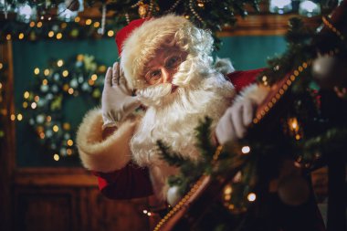 Mutlu Noeller ve mutlu yıllar! Neşeli Noel Baba duruyor ve güzel bir yeni yıl arifesinde tahta bir merdivende dinliyor.. 