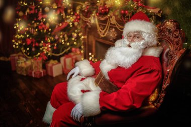 Noel Baba güzel bir Noel arifesinde bir koltukta oturur. Noel ve Yeni Yıl kavramı. 