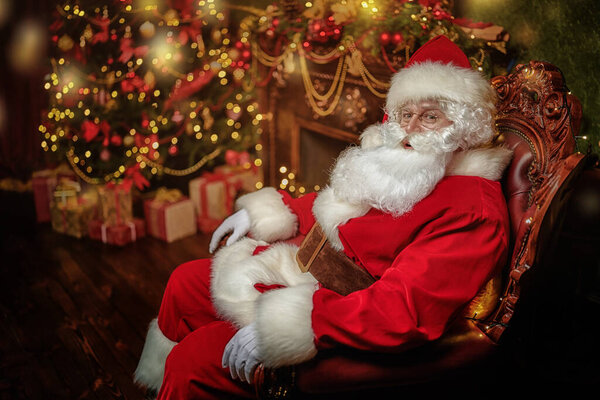 Санта Клаус сидит в кресле в красивом рождественском интерьере. Концепция Рождества и Нового года. 