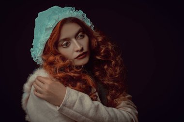 Portrait of a beautiful young woman with long red hair wearing medieval clothes on a dark background. Historical reconstruction of the Middle Ages. clipart