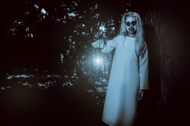 Ormanda fenerli korkunç solgun bir kızın portresi. Zombi, Cadılar Bayramı.