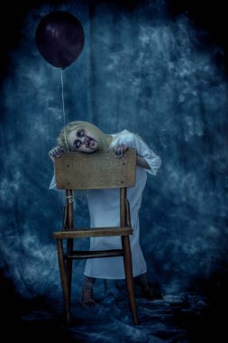 Arka planda sandalyenin yanında siyah balonlu korkunç soluk bir kızın portresi. Zombi, Cadılar Bayramı.