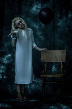 Arka planda sandalyenin yanında siyah balonlu korkunç soluk bir kızın portresi. Zombi, Cadılar Bayramı.