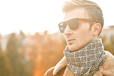 Sonbahar şehrinin arka planında, güneş gözlüklü zarif yakışıklı bir adamın sonbahar portresi.. 