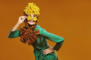 Modern pin-up tarzı. Zarif giysiler içinde, başında mimoza çiçekleri ve gözlükleriyle gülümseyen muhteşem kadın modeli. Parlak doymuş renkler.
