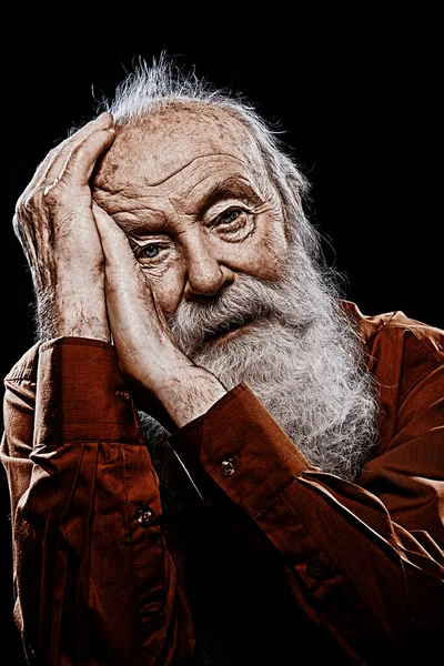 Old age concept. Portrait of an old man with white beard looking at camera. Black background.