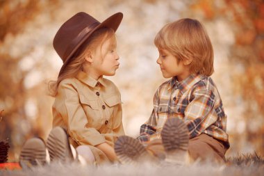 Komik romantik çocuklar erkek ve kız güzel bir sonbahar parkında birlikte vakit geçiriyorlar. Çocuk modası. Retro biçimi.