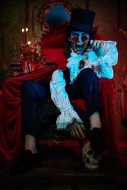 Kana susamış vampir, eski kalesinde gecenin bir yarısı kafatasıyla otururken dişlerini gösterdi. Kont Drakula. Cadılar Bayramı.