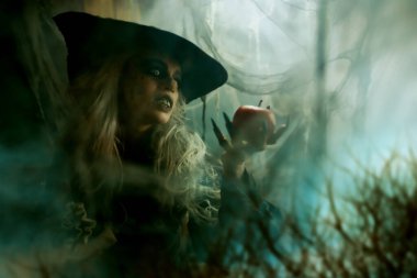 Cadılar Bayramı. Korkunç yaşlı cadı ormanda bir elma tutuyor..