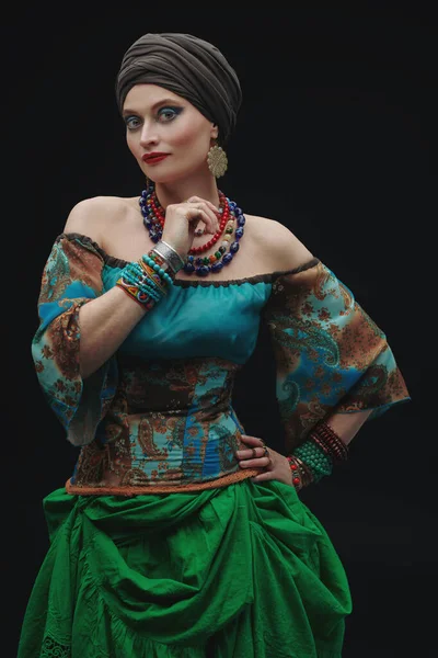 Portrait of a beautiful gypsy woman on a black background. Studio shot. National gypsy costume, ethnic.