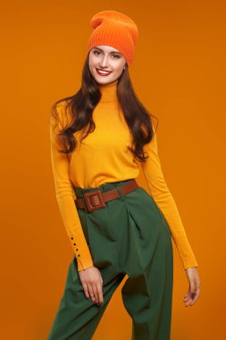 Renkli sonbahar kıyafetleri içinde kameraya gülümseyen güzel bir kızın portresi. Sarı arka planda hippi kız portresi. Moda fotoğrafı..