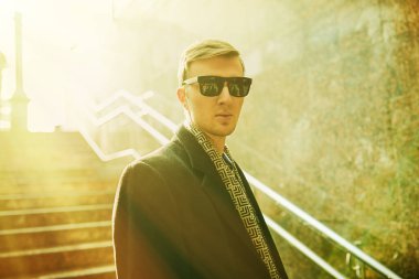 Bir sonbahar günü güneşin aydınlattığı bir alt geçitten merdivenlerden çıkan bir adam. Şehirde hayat..