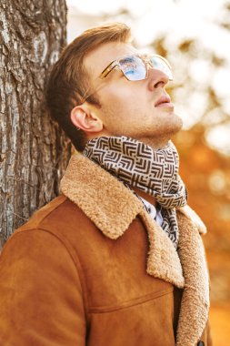 Sonbahar parkının arka planında gözlüklü zarif yakışıklı bir adamın sonbahar portresi.. 