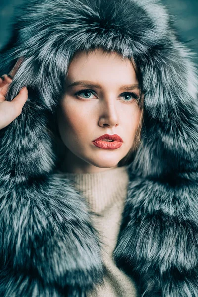 Portrait of a gorgeous fashionable woman in a silver fox fur coat with hood. Winter fur coat fashion.