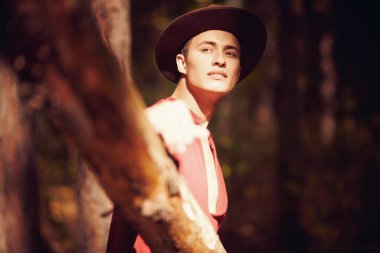 Gün batımında ormanda yakışıklı bir genç adam. Erkek güzeli. Macera, özgürlük ruhu. Etkin yaşam biçimi. 