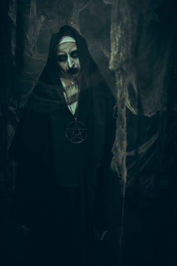 Terk edilmiş kilisede duran lanetli bir rahibenin portresi. Korku ve Cadılar Bayramı. 