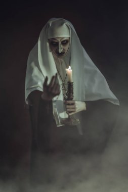 Şeytani ele geçirilmiş bir rahibe elinde bir mumla onu karanlıktan çağırır. Korku ve Cadılar Bayramı.