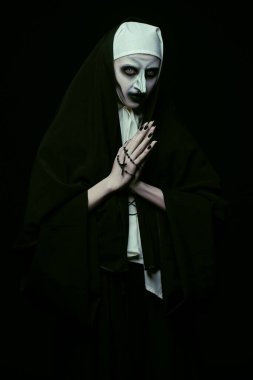 Cadılar Bayramı. Siyah bir arka planda elinde haçla korkunç bir rahibenin portresi. Dehşet.